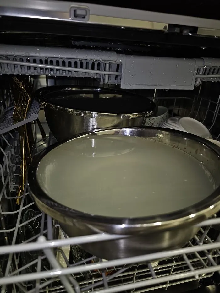 A dishwasher loaded with large metal mixing bowls filled with water, shown as one of many absurd products and situations.