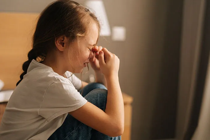 A distressed child crying indoors in someone's home