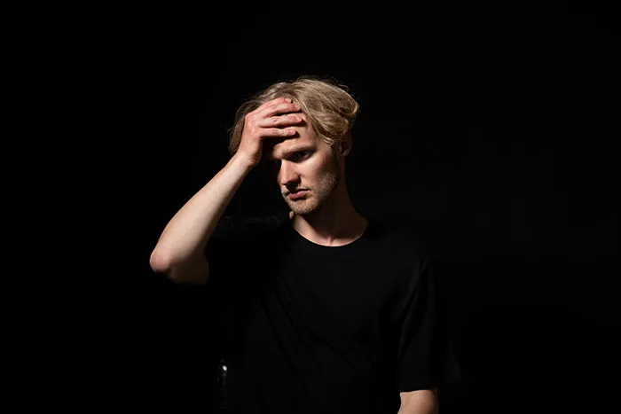A man holding his forehead in distress, illustrating unsettling things spotted in someone's home.