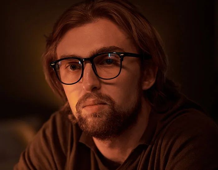 A man with glasses staring intently, representing unusual things spotted in someone's home.