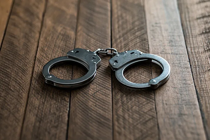 Metal handcuffs resting on a wooden table, one of the concerning things spotted in someone's home.