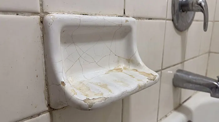 A cracked and dirty ceramic soap dish in a bathroom, one of the unpleasant things spotted in someone's home.
