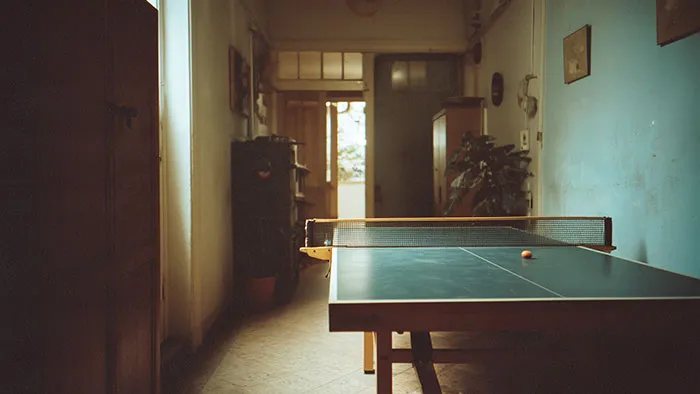 A ping pong table set up inside a narrow hallway of a home