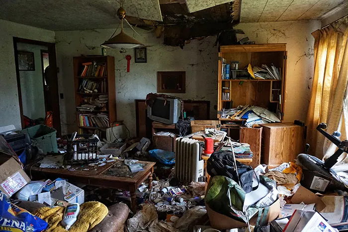 An extremely messy and cluttered room in someone's home with garbage everywhere.