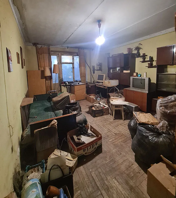 A messy and cluttered room in someone's home filled with boxes and old furniture