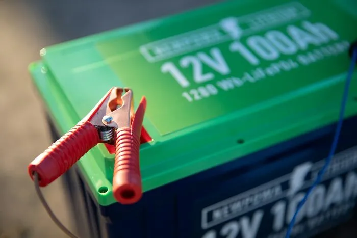 A 12V 100Ah car battery with jumper cables attached during petty relationship fights