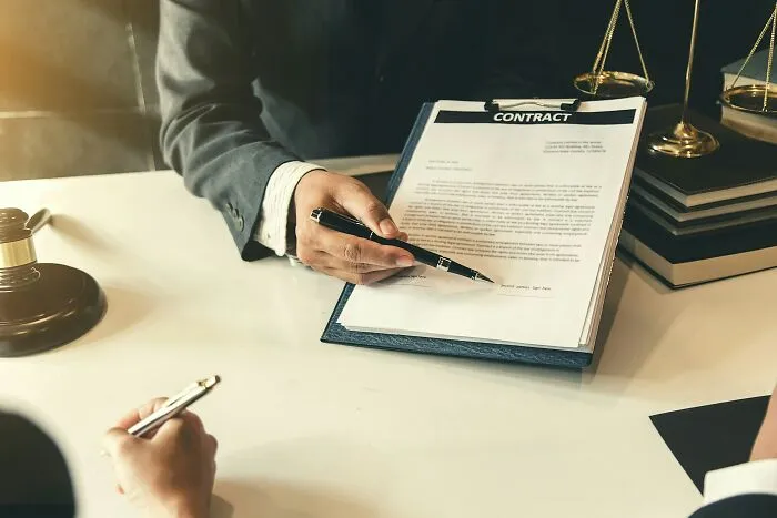 A lawyer holding a pen pointing at a legal contract document in a tiny community case.