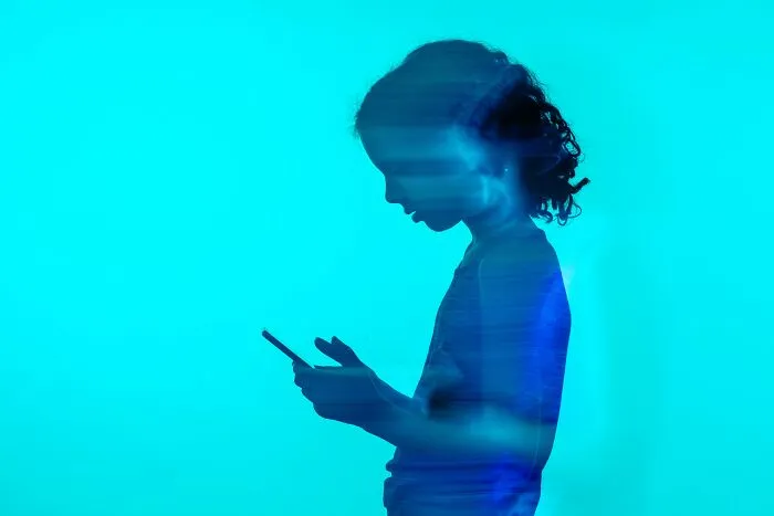 A silhouette of a child looking at a smartphone, representing mental health problems in Gen Z.