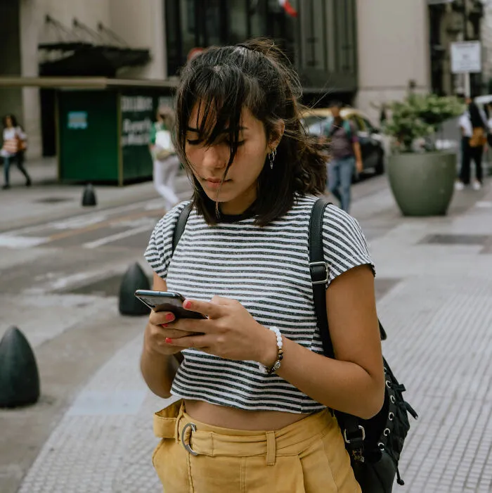 A young woman looking at her phone while walking outside, capturing a scene related to things strangers said.