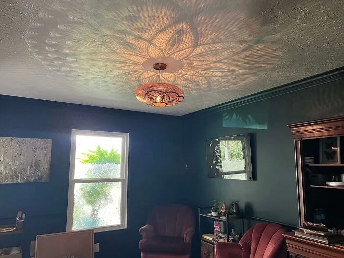 Living room home makeover with dark green walls and unique ceiling light shadow pattern
