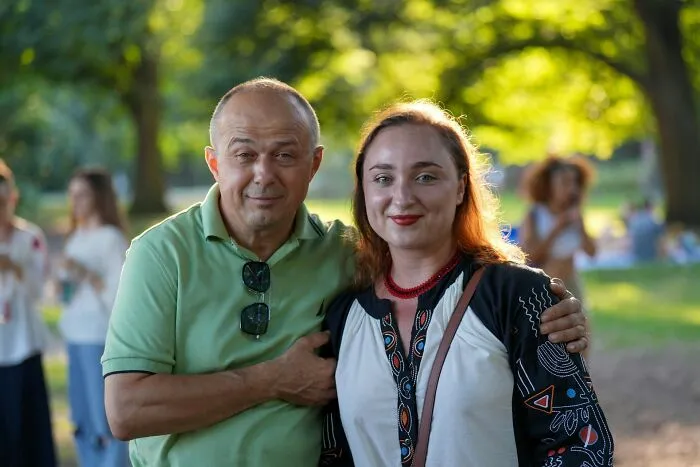 Smiling couple posing together outdoors in a park surrounded by green trees and nature