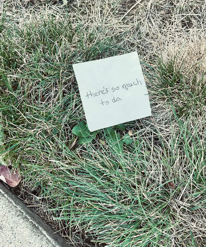 A small note resting on grass that says there is so much to do, featuring found paper.