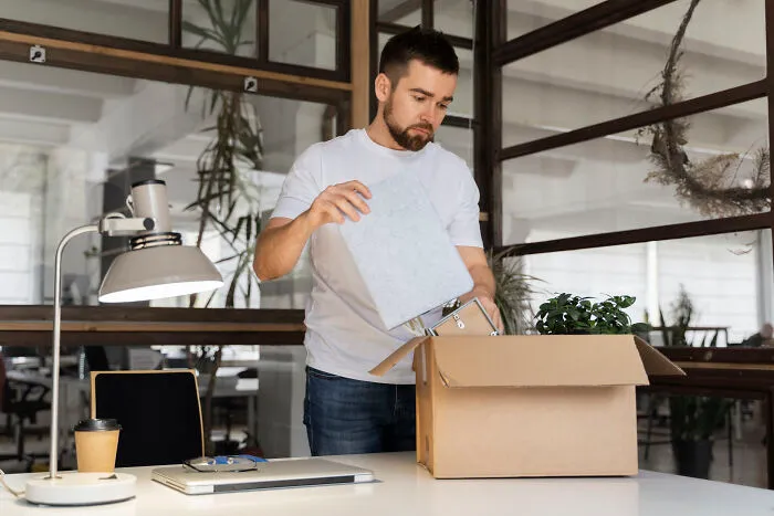 A man packing his office belongings into a cardboard box after leaving one of people's jobs