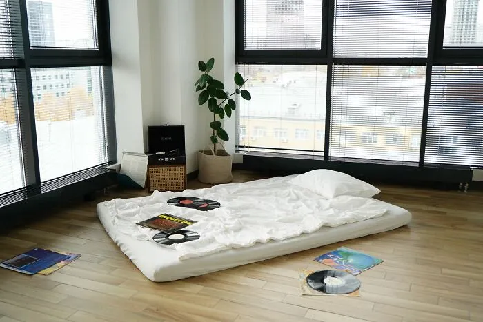 Minimalist bedroom with floor mattress and vinyl records near large windows
