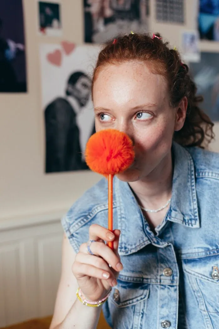 Person holding an orange fuzzy pom-pom pen instead of candy while trick-or-treating.