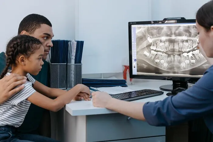Dentist showing dental x-ray to father and daughter about microaggressions women experience