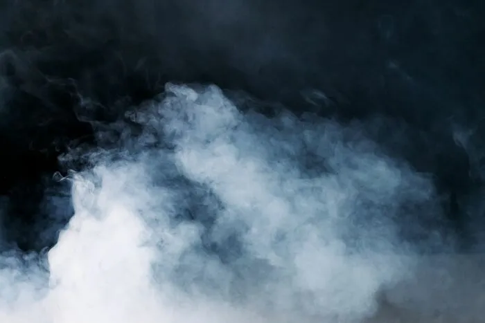 Thick white smoke rising dramatically against a dark background