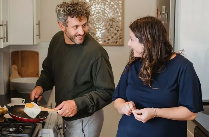 A man cooking an egg for a woman in a kitchen, representing surprising laws and loopholes regarding daily life.
