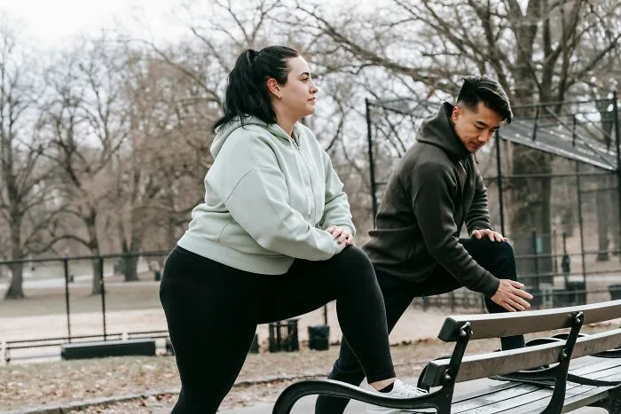 Woman stretching with trainer in outdoor fitness park