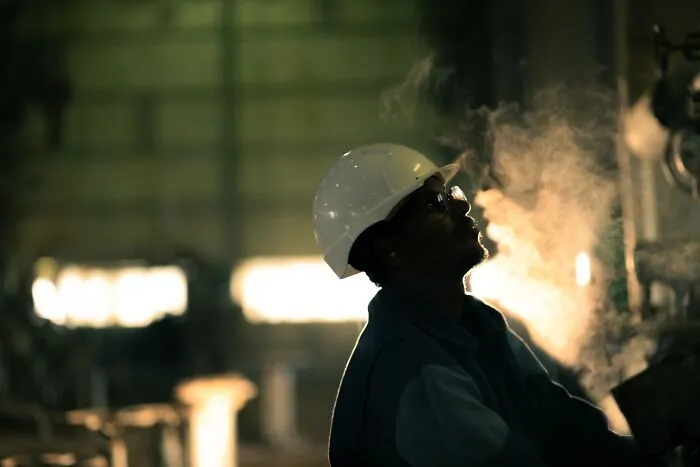 Industrial worker looking up at steam, avoiding a dangerous and expensive slip-up
