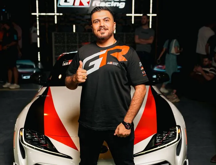 A man posing next to a custom sports car after a costly slip-up