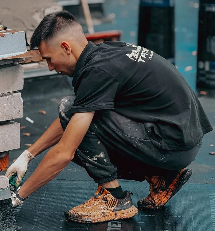 Construction worker kneeling while laying materials, demonstrating precision to prevent a slip-up