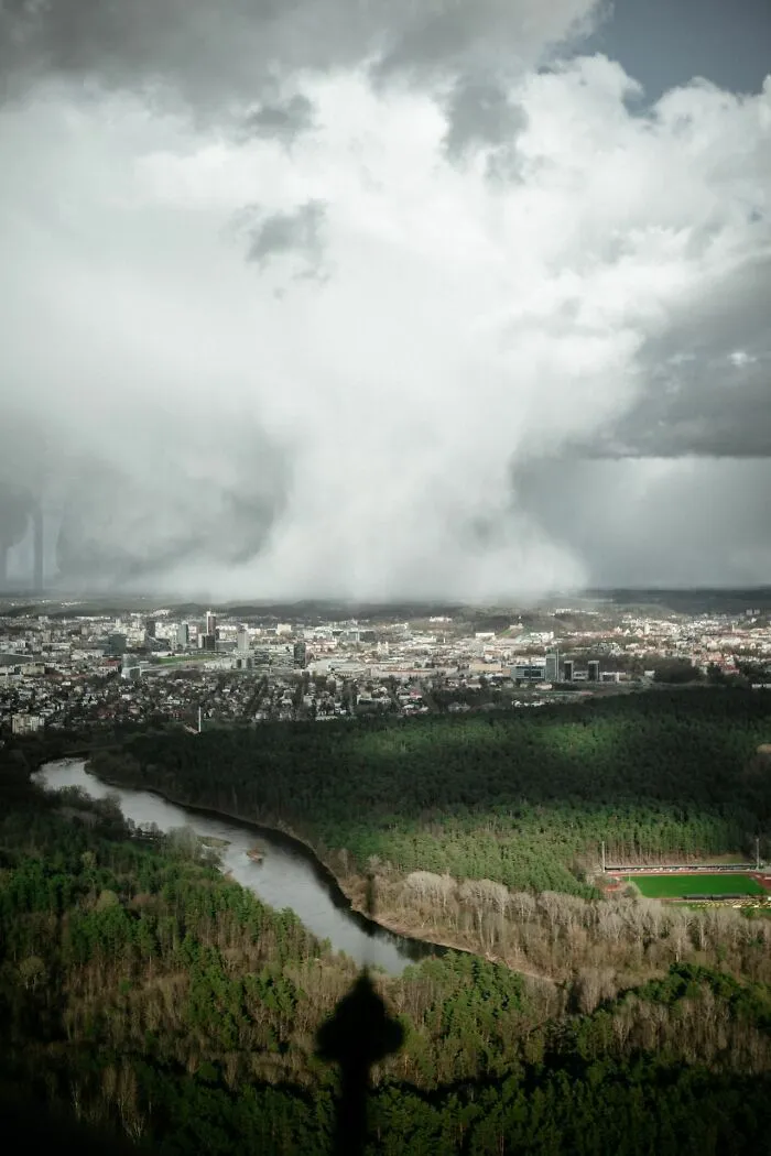 A massive storm cloud approaching a city, invoking an urgent feeling to leave immediately
