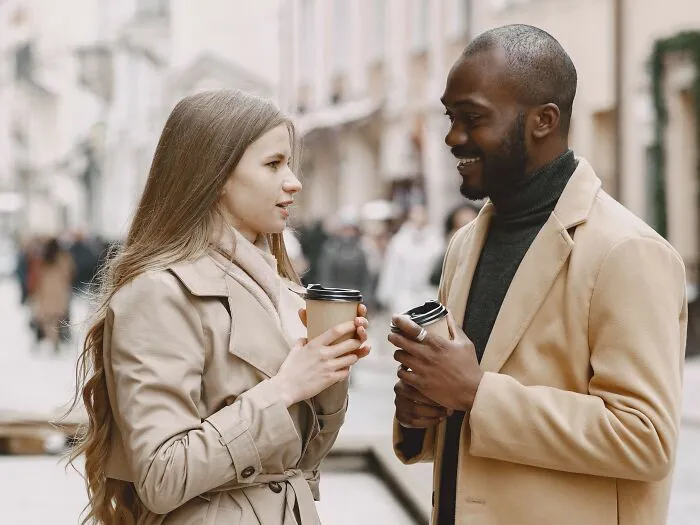 Woman and man talking with coffee cups in street discussing microaggressions women hear