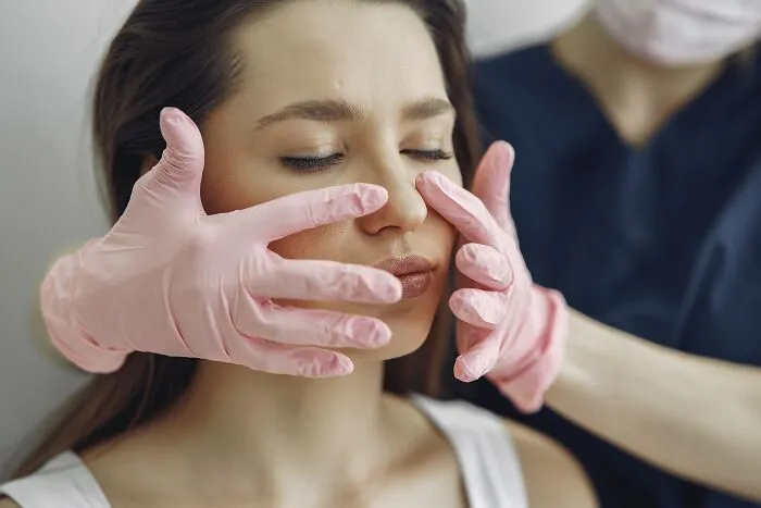 A doctor in pink gloves touching a patient's face, showing dumb things professionals said or did.