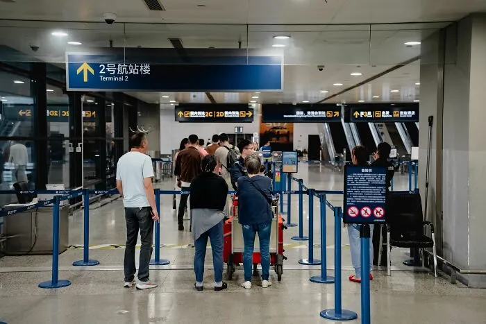 Passengers waiting in queue at airport terminal, looking at digital maps for brilliant travel tips.