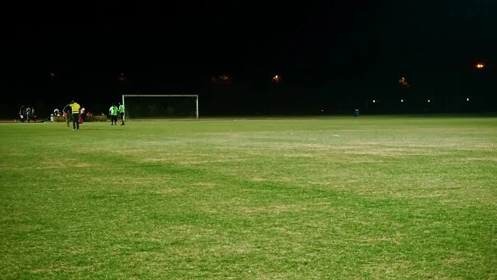 Empty soccer field at night where tiny communities gather and experience drama