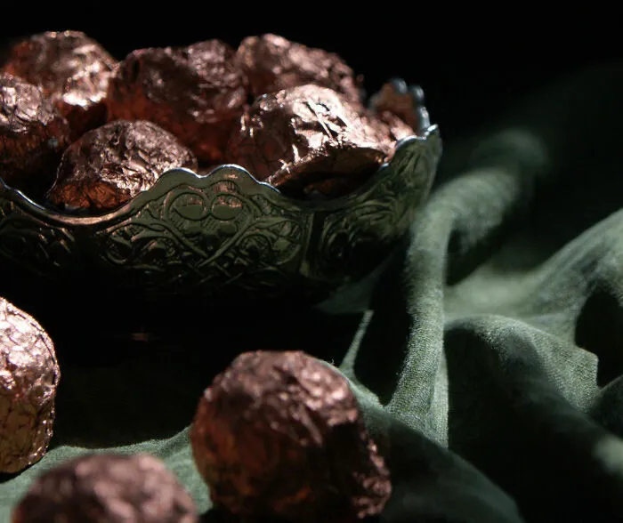 Foil-wrapped chocolates displayed in a decorative bowl given out during trick-or-treating.