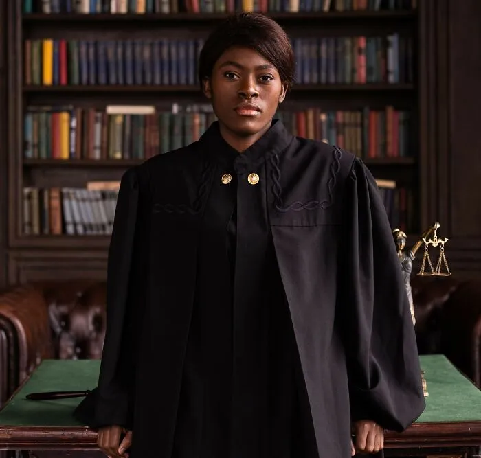 A female judge standing in a study with bookshelf background representing real laws and loopholes