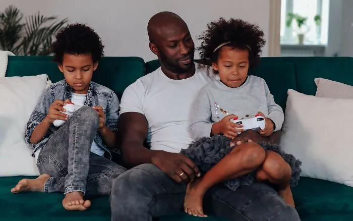 Father with two children playing video games on couch representing microaggressions