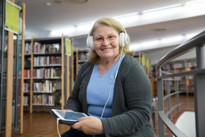 A woman with headphones in a library showing brilliant tips on how to enjoy audiobooks easily