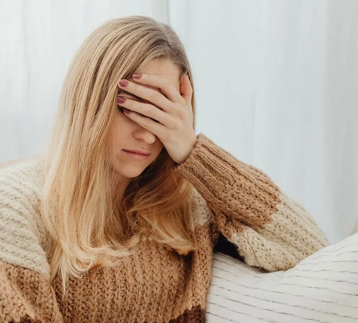 A woman covering her face with her hand, depicting chilling stories of people sensing something off.