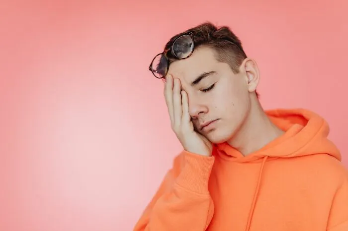 Embarrassed teen in orange hoodie recalling Karen experiences