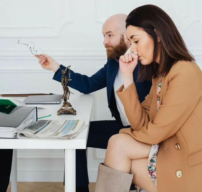 A woman sitting anxiously at a desk next to legal books, representing real laws and loopholes.
