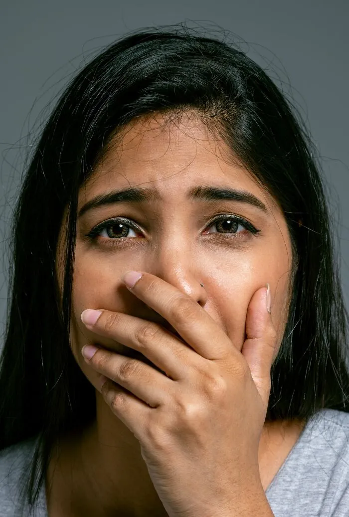 A worried woman covering her mouth in fear, evoking an urgent feeling to leave immediately