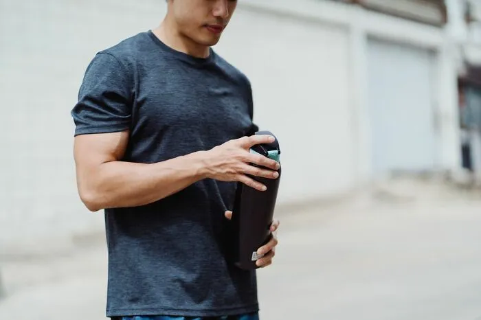 Man opening a modern water bottle, demonstrating clever life tricks for daily hydration and fitness.