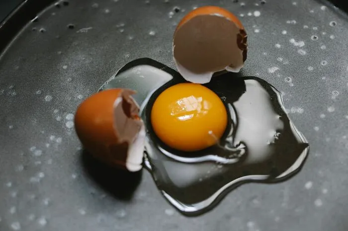 A cracked raw egg with yolk on a dark surface instead of candy while trick-or-treating.