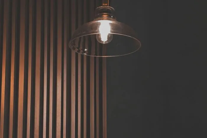 An illuminated ceiling light hanging against a dark background symbolizing obvious lies.