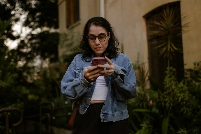 Woman looking at her phone, reflecting a funny instance of an embarrassing fail.