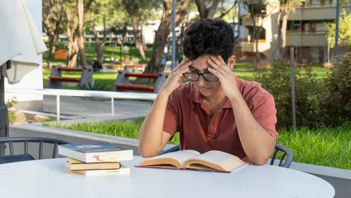 A stressed student holding his head while studying, demonstrating clever life tricks for productivity