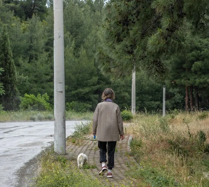 A person walking with their dog on a path, experiencing an urgent feeling to leave immediately.