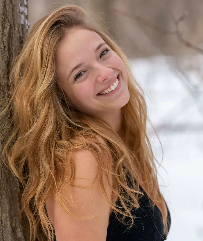 Smiling blonde woman leaning against a tree outdoors. Life lessons and things women wish they knew.