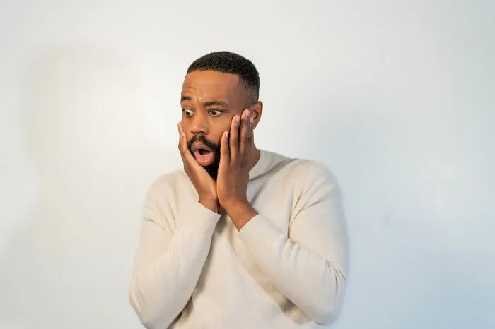 A shocked man with hands on his face, reacting to an urgent feeling or frightening news