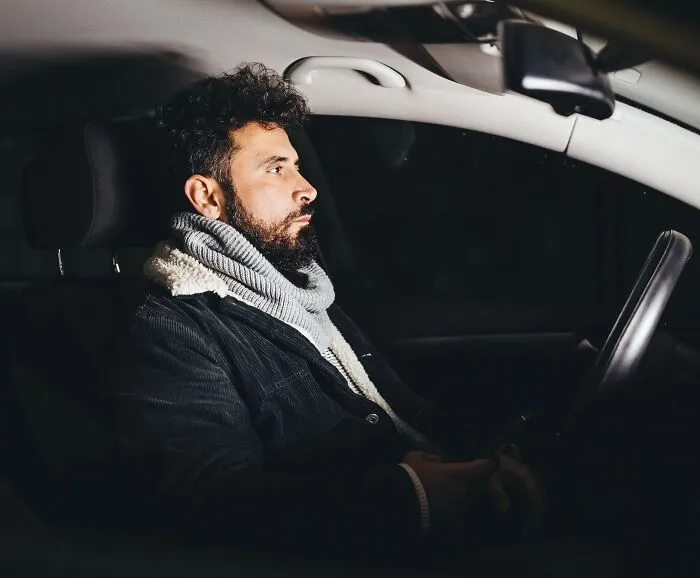 A man sitting in a car at night, representing chilling stories of trusting one's gut feeling.