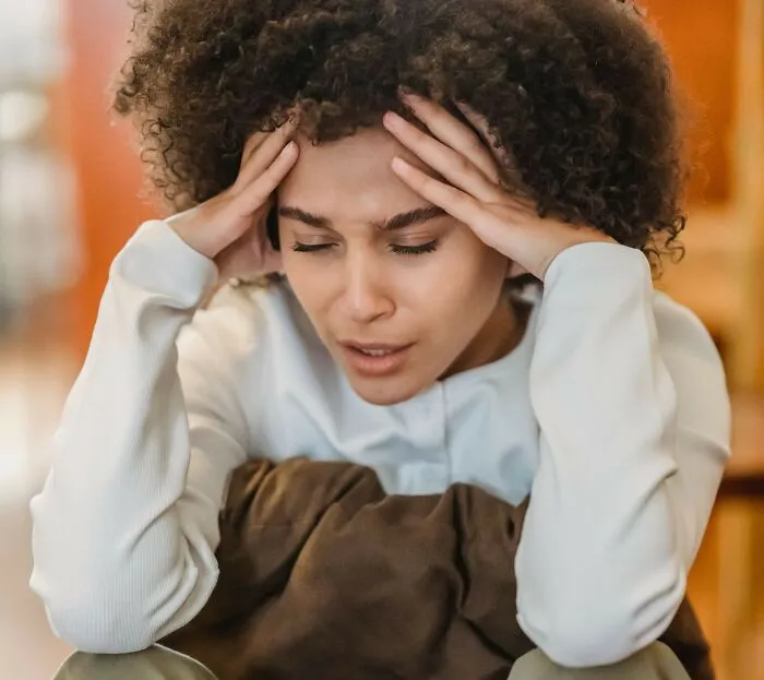 Woman holding her temples in stress. Essential things women wish they had known sooner in life.