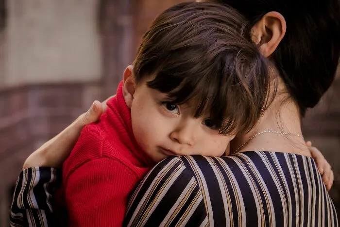 Mother holding her young child resting on her shoulder, illustrating laws and legal rights.
